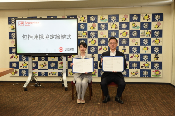 写真：署名した協定書を掲げる株式会社ブランジスタメディア井上代表と森田市長